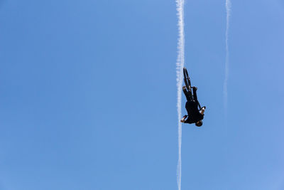 Man performing stunt with bicycle against blue sky