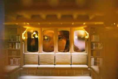 Portrait of woman looking through illuminated window