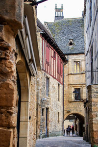 People walking on alley amidst buildings in city