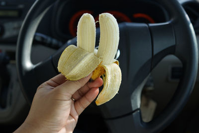 Cropped hand holding banana in car