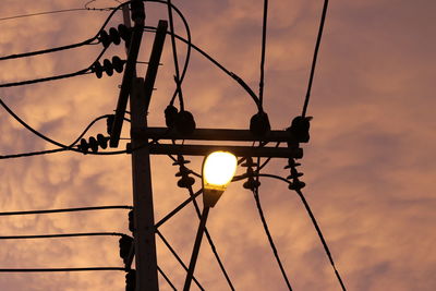 Low angle view of silhouette electricity pylon against sky during sunset