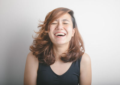 Portrait of smiling young woman against white background