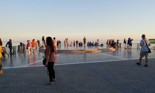 Group of people walking on shore against clear sky