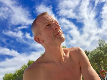 Low angle view of shirtless mature man against sky