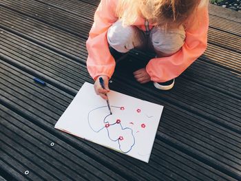 High angle view of baby girl drawing while crouching outdoors