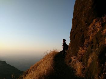 Man standing on mountain against sky during sunset