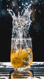 Close-up of glass splashing on table against black background