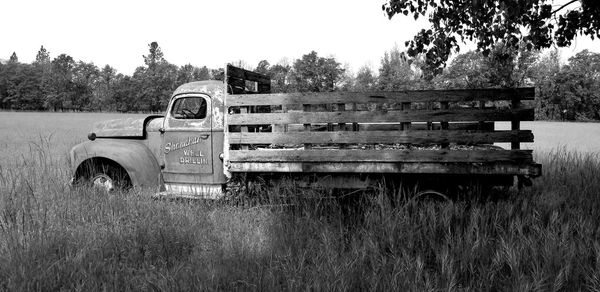 Abandoned truck on field against clear sky