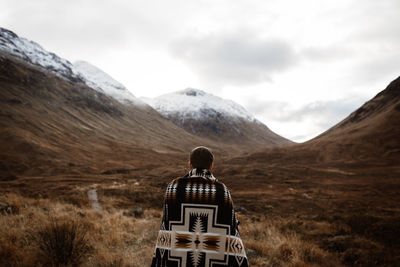 Rear view of man on mountain against sky