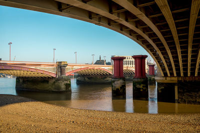 Arch bridge over river against clear sky