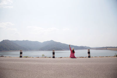 Rear view of woman on beach against sky