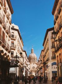 People on street amidst buildings against sky in city