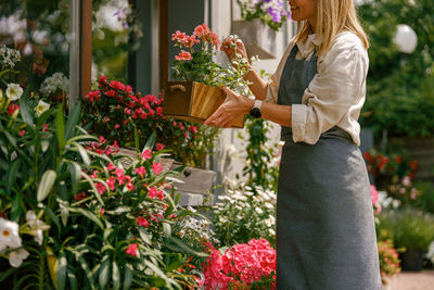 Young woman standing by flowers