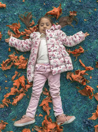 Full length portrait of happy girl playing in autumn
