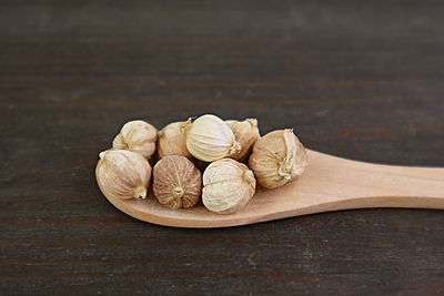 Spoon of white cardamom seeds on black wooden background