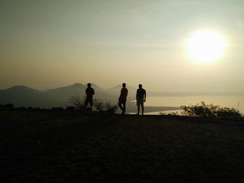 Friends standing on landscape at sunset