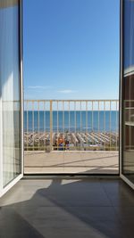 View of sea against clear blue sky seen through window