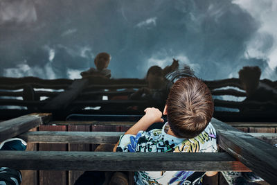 View from above of boy looking down at lake water surface