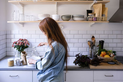 Woman cooking food by kitchen counter at home