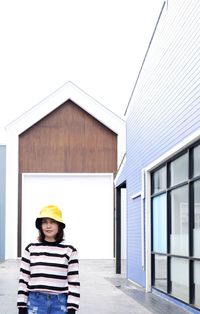 Woman standing outside house against building