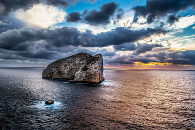 Rock formation on sea against sky during sunset