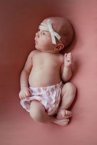 Cute baby girl lying on pink background