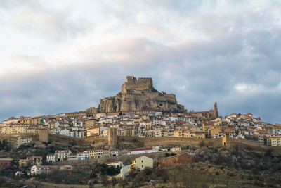 Buildings in town against cloudy sky