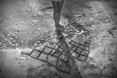 Low section of woman standing on puddle