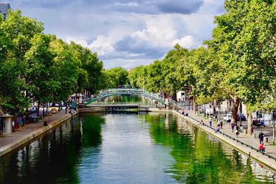 People on bridge over trees against sky