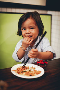 Portrait of cute girl eating food at home