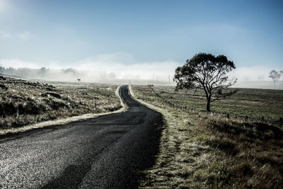 Road amidst field against sky