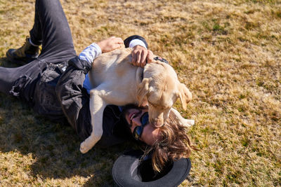 Portrait of young tattoed man playing with his dog in the countryside