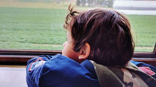 Rear view of boy looking through train window