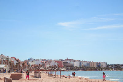 People on beach against sky in city