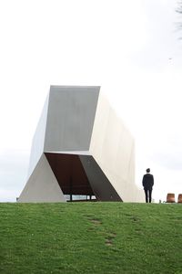 Man standing by modern building against sky
