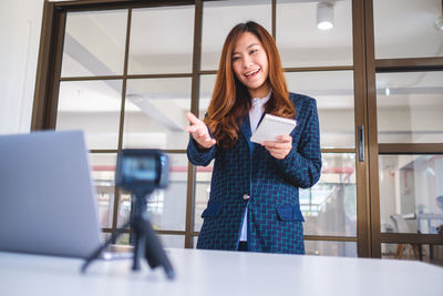 Smiling businesswoman blogging in office