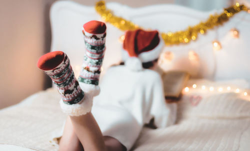 The girl is reading a book lying on the bed.