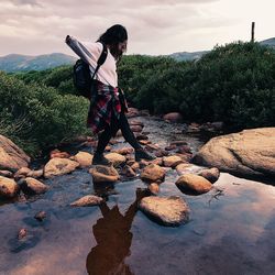 Full length of woman walking on rocks in river