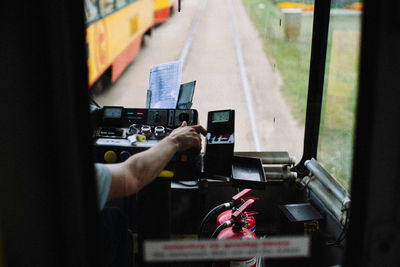Cropped hand of driver driving bus seen through window
