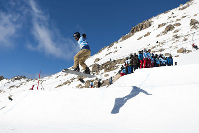 Low angle view of people skiing on snowcapped mountain