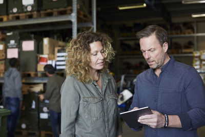 Mature colleagues discussing over digital tablet at warehouse