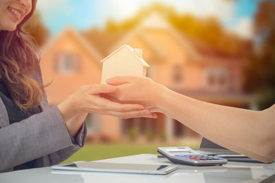 Cropped hands giving model home to female customer