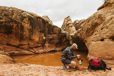 Rear view of people on rock formation against sky