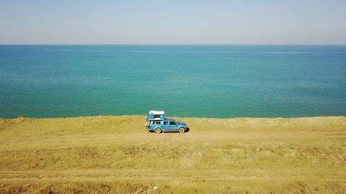 Vintage car on field by sea against clear sky