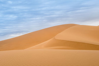 Sand dunes in desert against sky