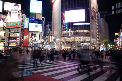 Crowd walking on illuminated city at night