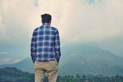 Rear view of man looking at mountain against sky