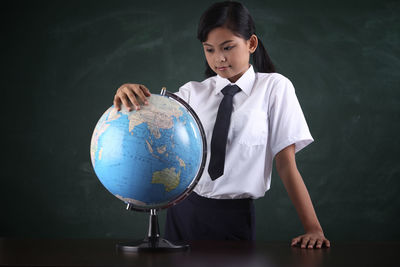 Schoolgirl with globe against blackboard