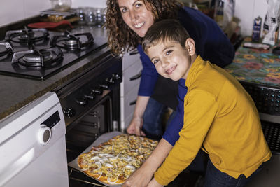 Mother and son putting a pizza in the oven