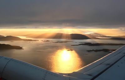 Airplane flying over sea against sky during sunset